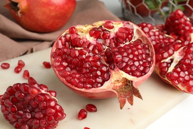 Photo of Piece of fresh pomegranate and seeds on white table, closeup