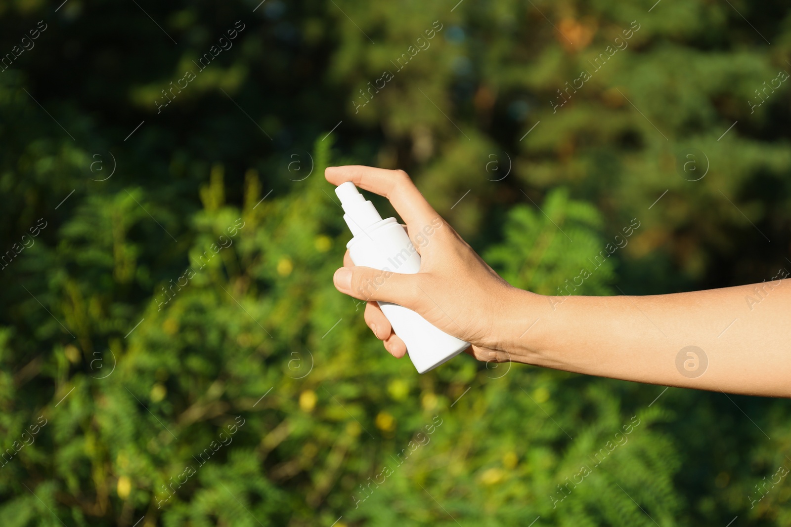 Photo of Woman holding insect repellent outdoors, closeup view