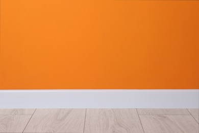 Photo of White plinth on laminated floor near orange wall indoors