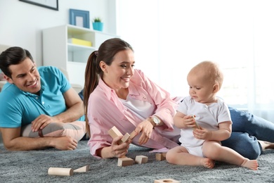 Happy mother playing with little baby on floor indoors