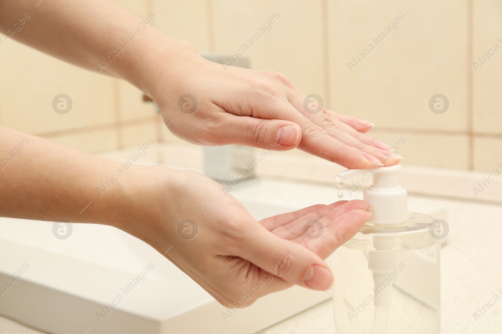 Photo of Woman applying antiseptic gel on hand in public bathroom, closeup