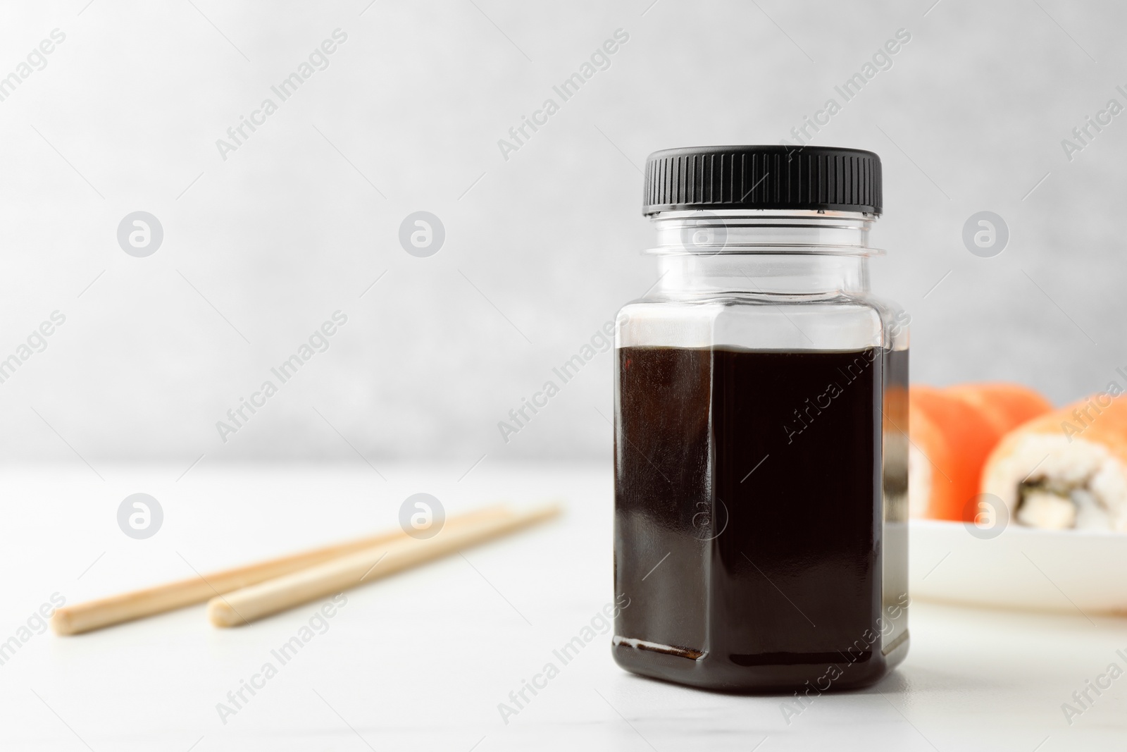Photo of Bottle of tasty soy sauce on white table. Space for text