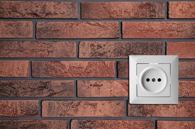 Image of Brick wall with power socket, space for text. Electrical supply