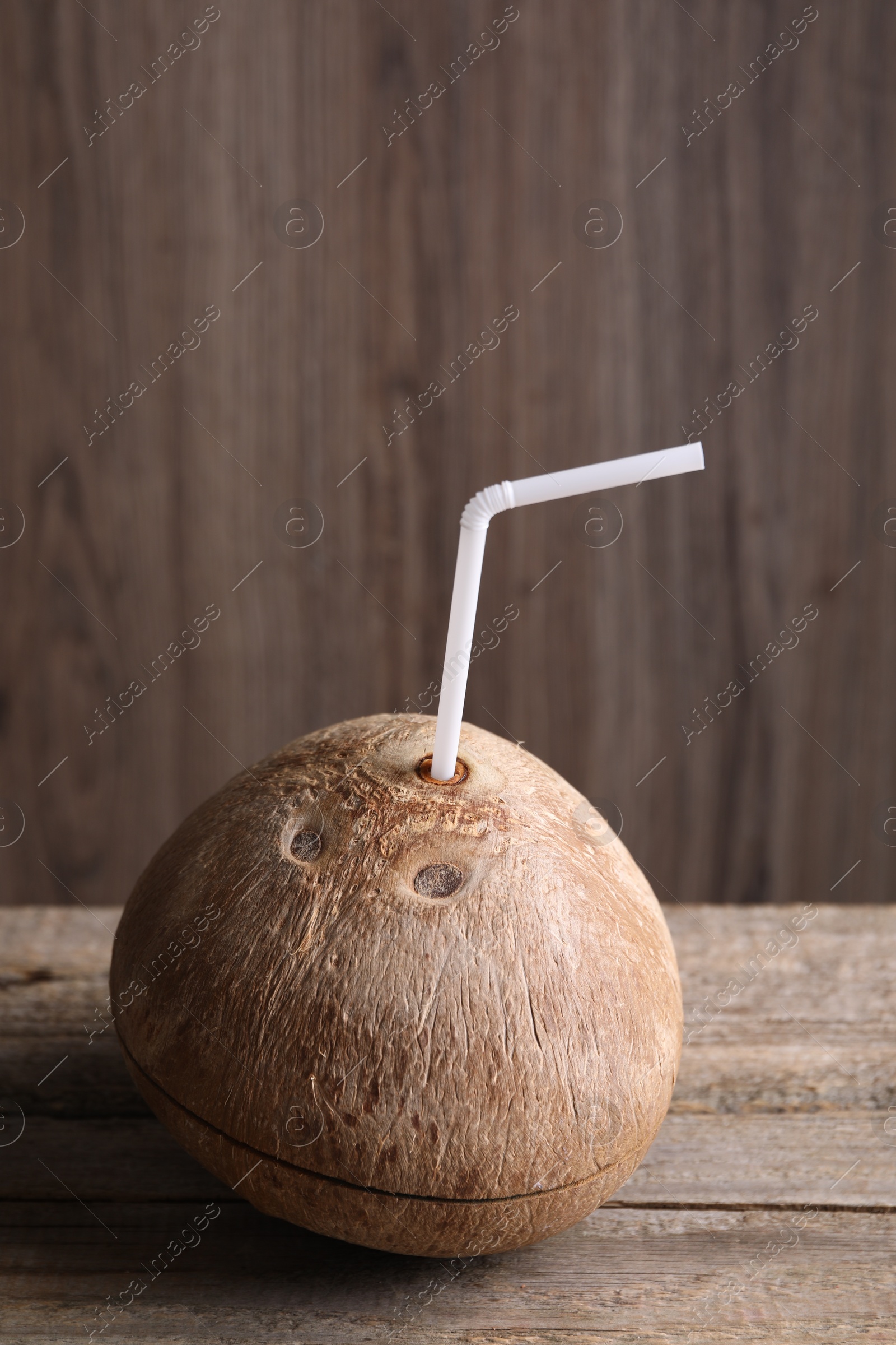 Photo of Coconut water. Fresh nut with straw on wooden table