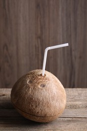 Photo of Coconut water. Fresh nut with straw on wooden table