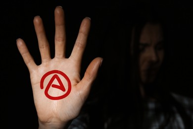 Image of Young woman showing palm with atheism sign in darkness, focus on hand