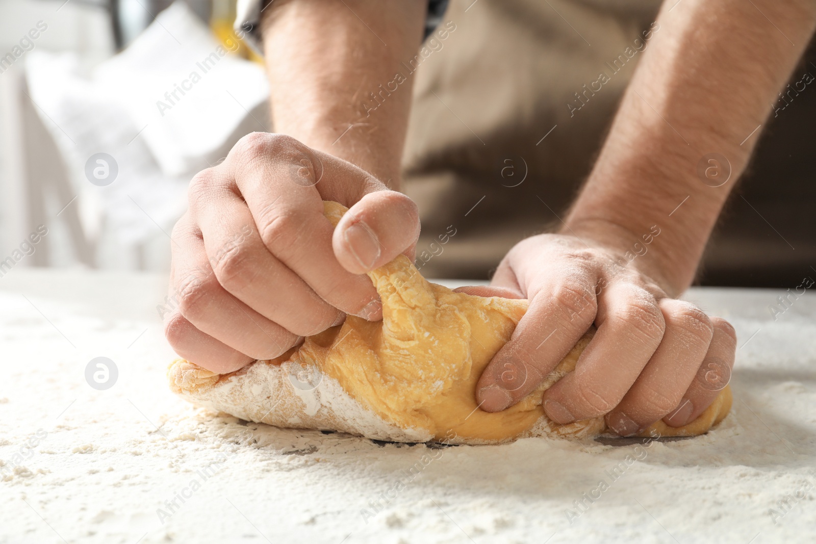 Photo of Young man kneading dough for pasta on table