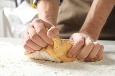 Young man kneading dough for pasta on table