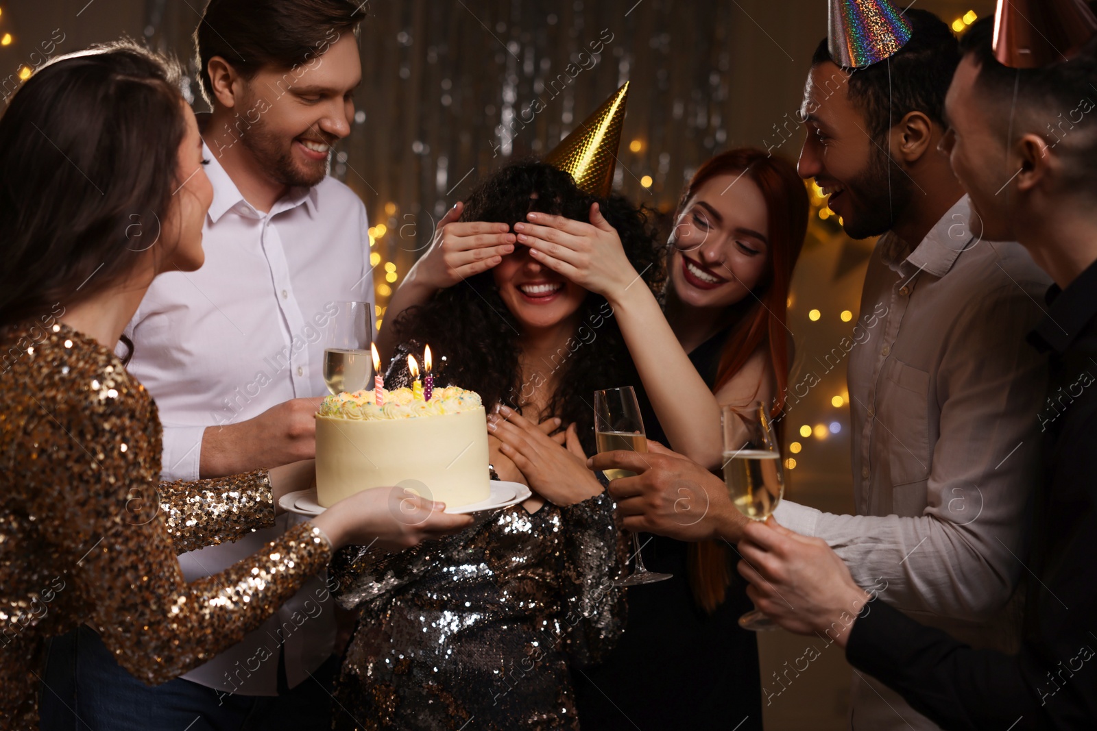 Photo of Happy friends with tasty cake and glasses of sparkling wine celebrating birthday indoors