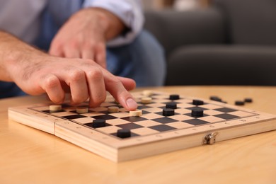 Man playing checkers at wooden table, closeup