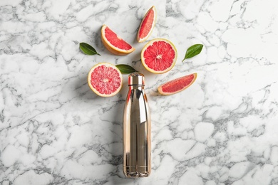 Flat lay composition with grapefruits and bottle of juice on marble background