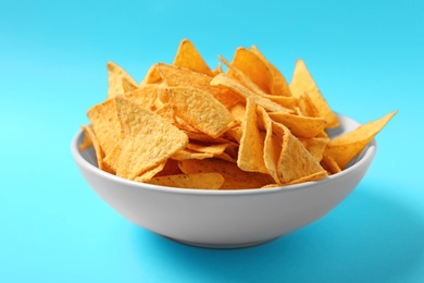 Photo of Tasty mexican nachos chips in bowl on blue background