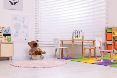 Photo of Stylish kindergarten interior with table, shelving unit and different toys