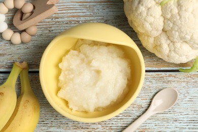 Baby food. Bowl with cauliflower puree and ingredients served on rustic wooden table, flat lay