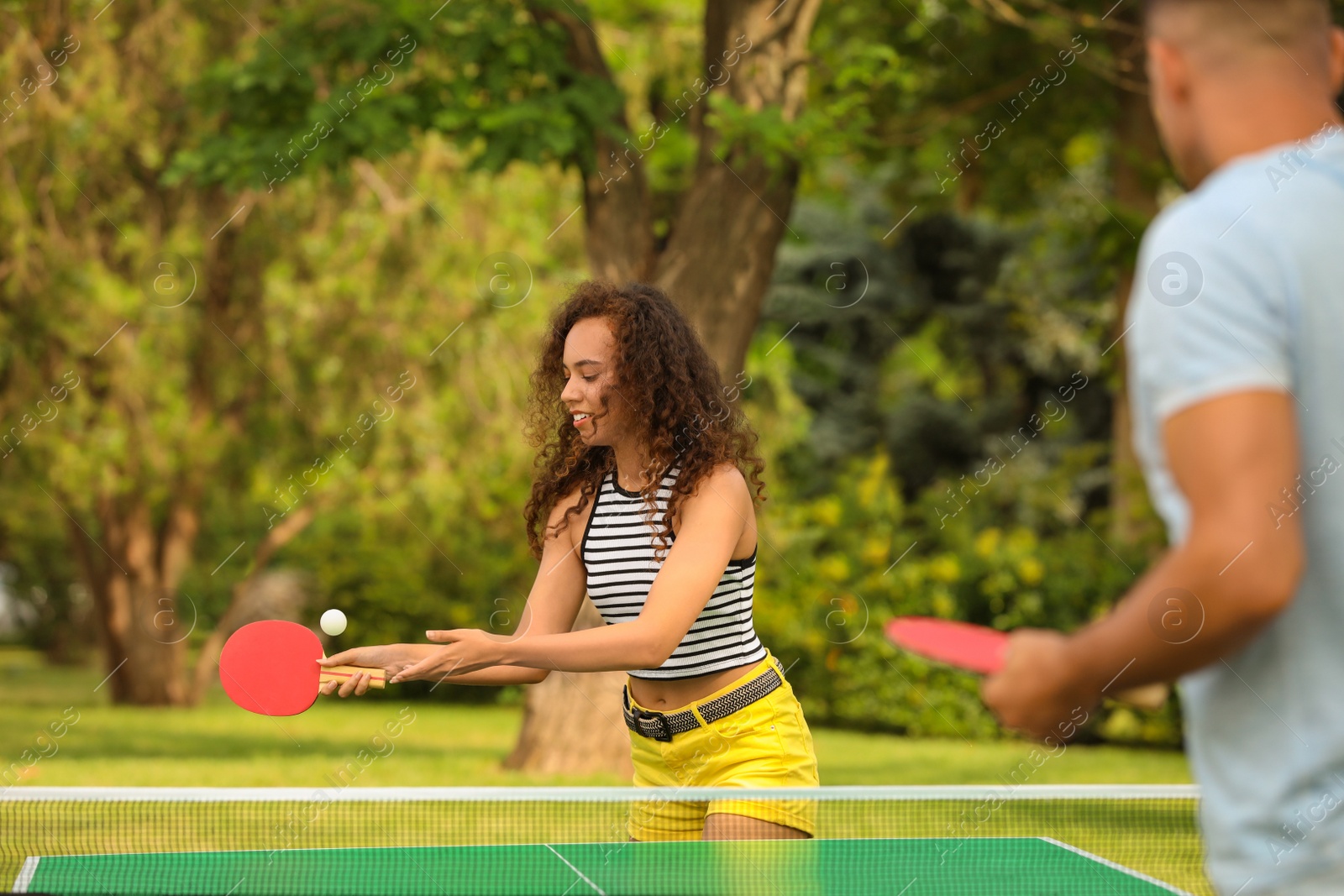 Photo of Friends playing ping pong outdoors on summer day