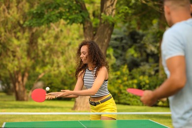 Friends playing ping pong outdoors on summer day