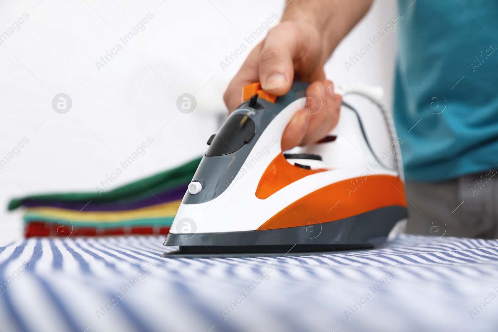 Photo of Man ironing shirt on board at home, closeup