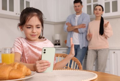 Internet addiction. Parents scolding their daughter while she using smartphone in kitchen