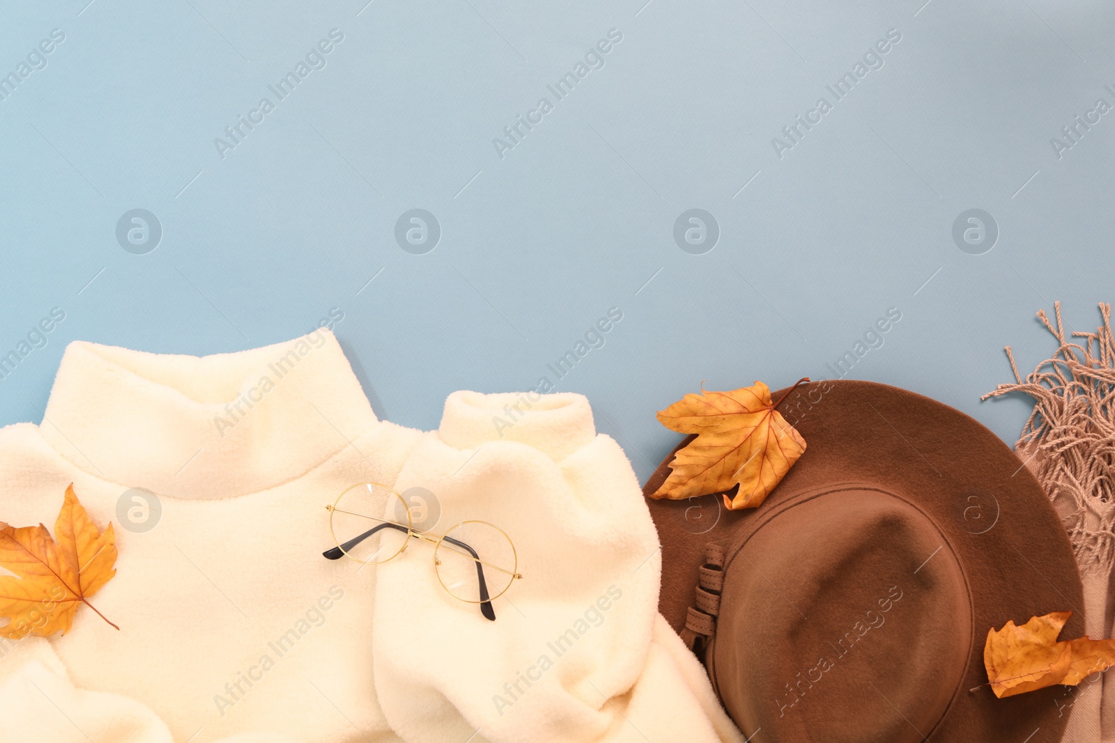 Photo of Flat lay composition with sweater and dry leaves on light blue background, space for text. Autumn season