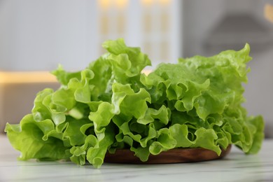 Photo of Fresh lettuce on white marble table, closeup. Salad greens