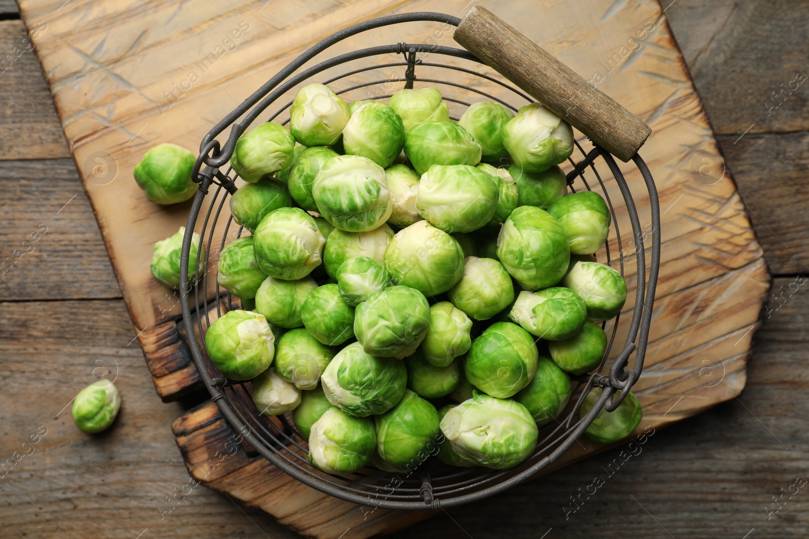 Photo of Metal basket with fresh Brussels sprouts on wooden background, top view