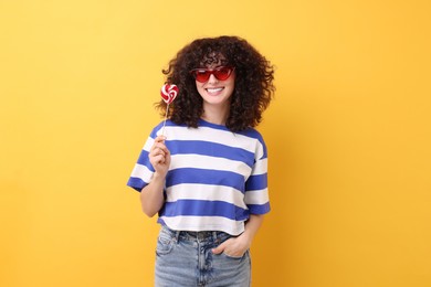 Photo of Beautiful woman in sunglasses with lollipop on yellow background