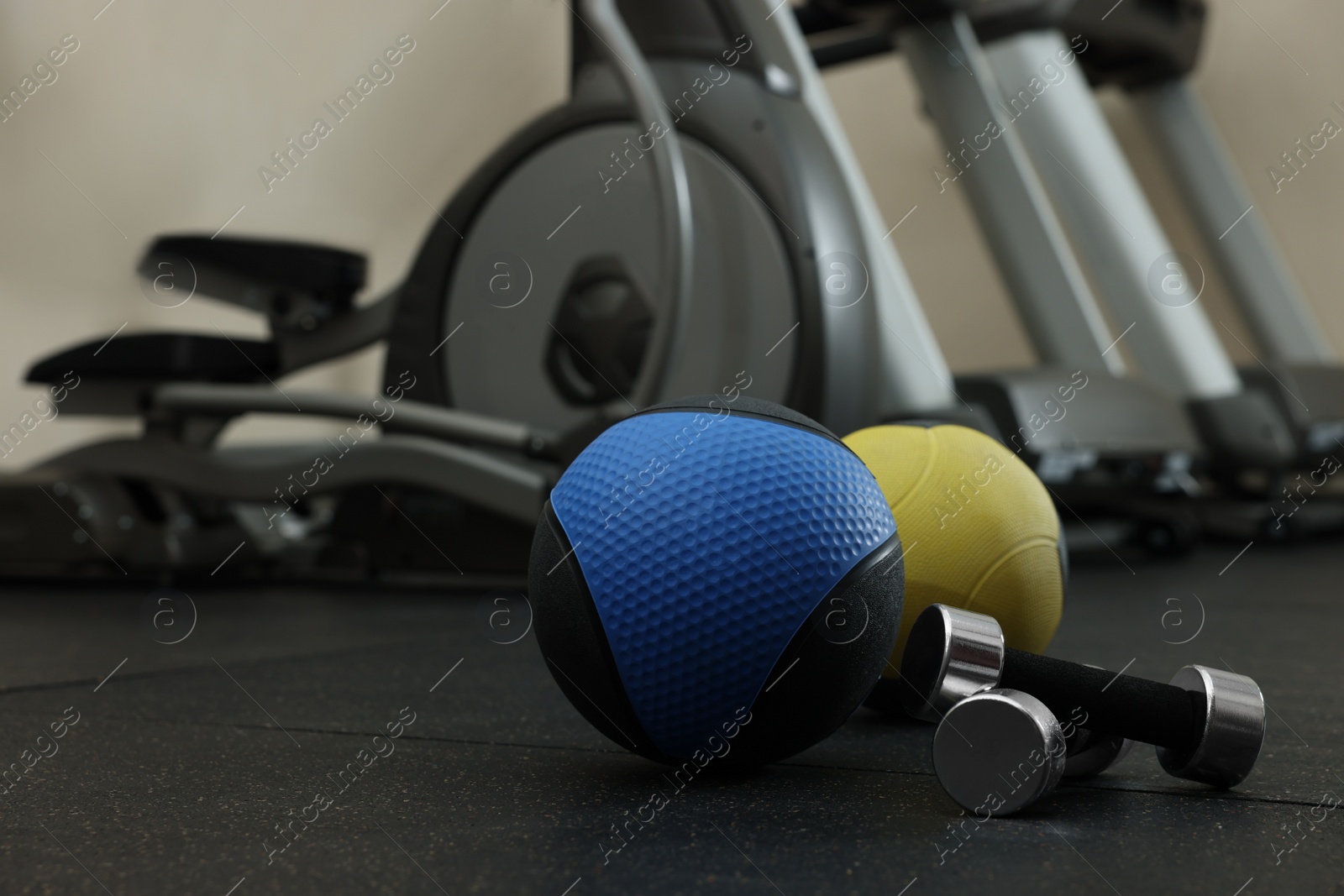 Photo of Medicine balls and dumbbells on floor in gym, space for text