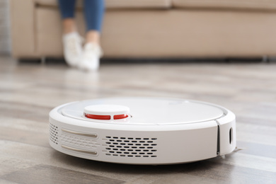 Photo of Woman resting while robotic vacuum cleaner doing her work at home