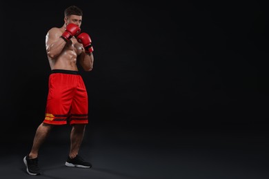 Man in boxing gloves on black background. Space for text