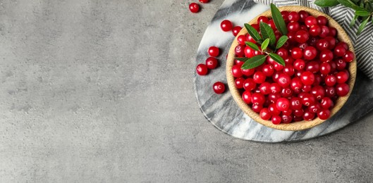 Tasty ripe cranberries on grey table, flat lay. Banner design with space for text