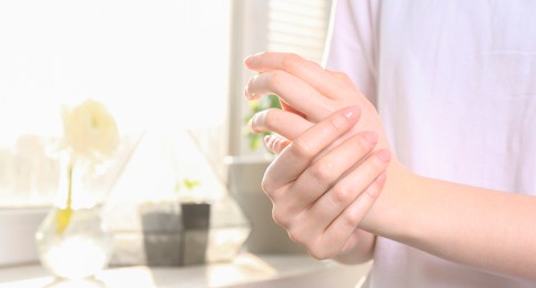 Woman applying hand cream at home, closeup