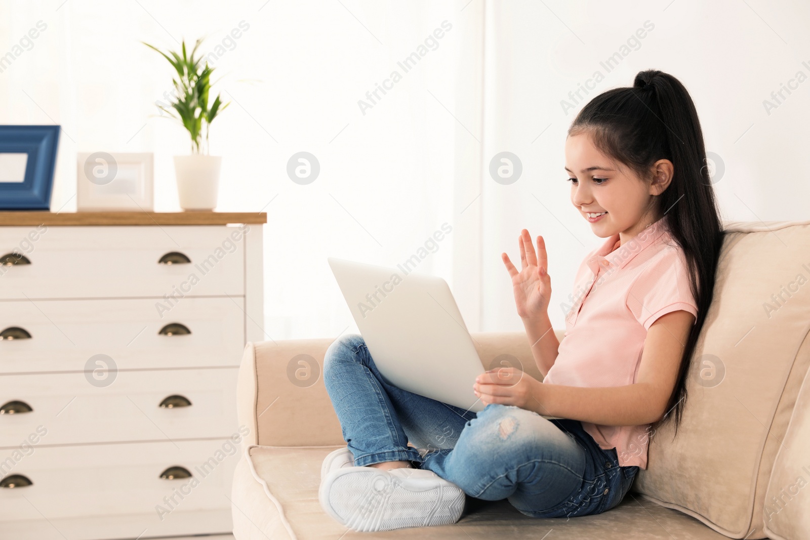 Photo of Little girl using video chat on laptop at home