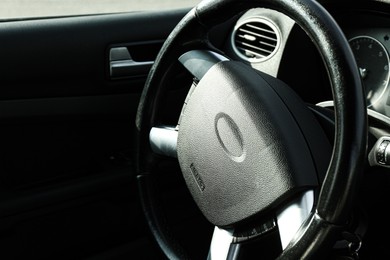 Photo of Black steering wheel in car, closeup. Space for text
