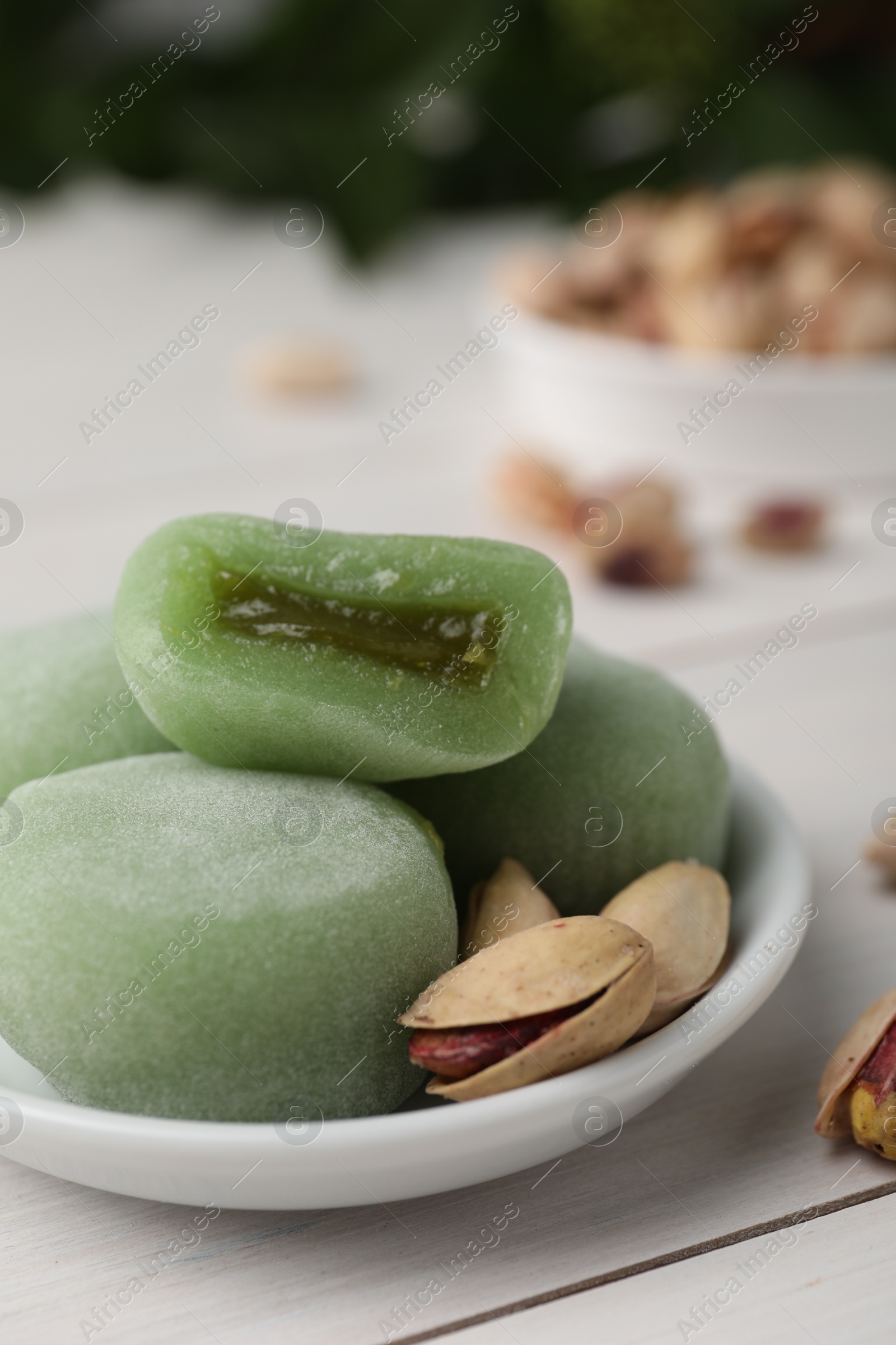 Photo of Delicious mochi and pistachios on white wooden table, closeup with space for text. Traditional Japanese dessert