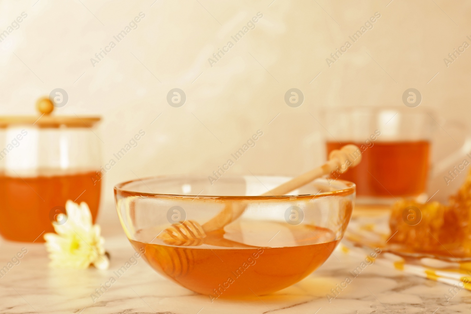 Photo of Glass bowl with tasty honey and dipper on marble table