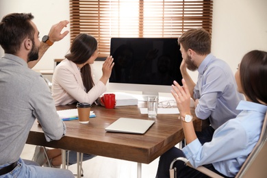 Photo of Group of colleagues using video chat on computer in office. Space for text