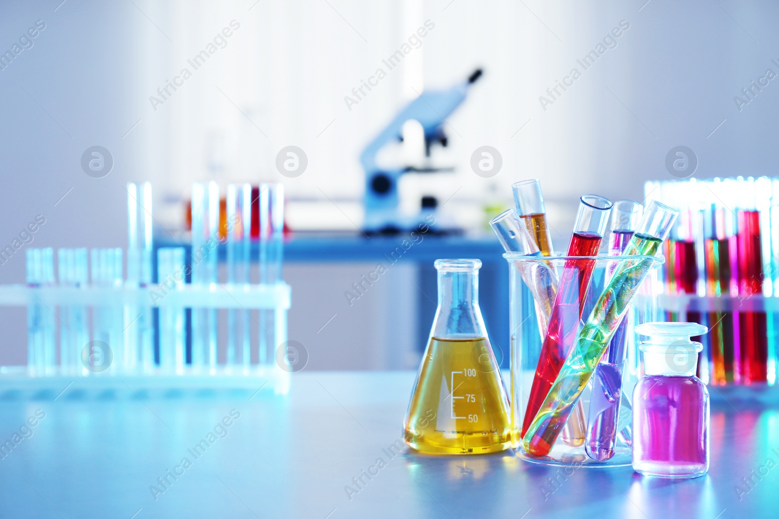 Photo of Chemistry glassware with liquids on table in laboratory. Space for text