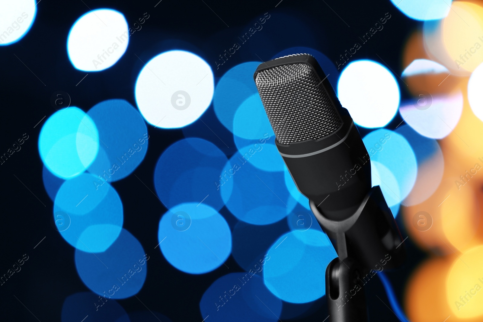 Photo of Microphone against festive lights, space for text. Musical equipment