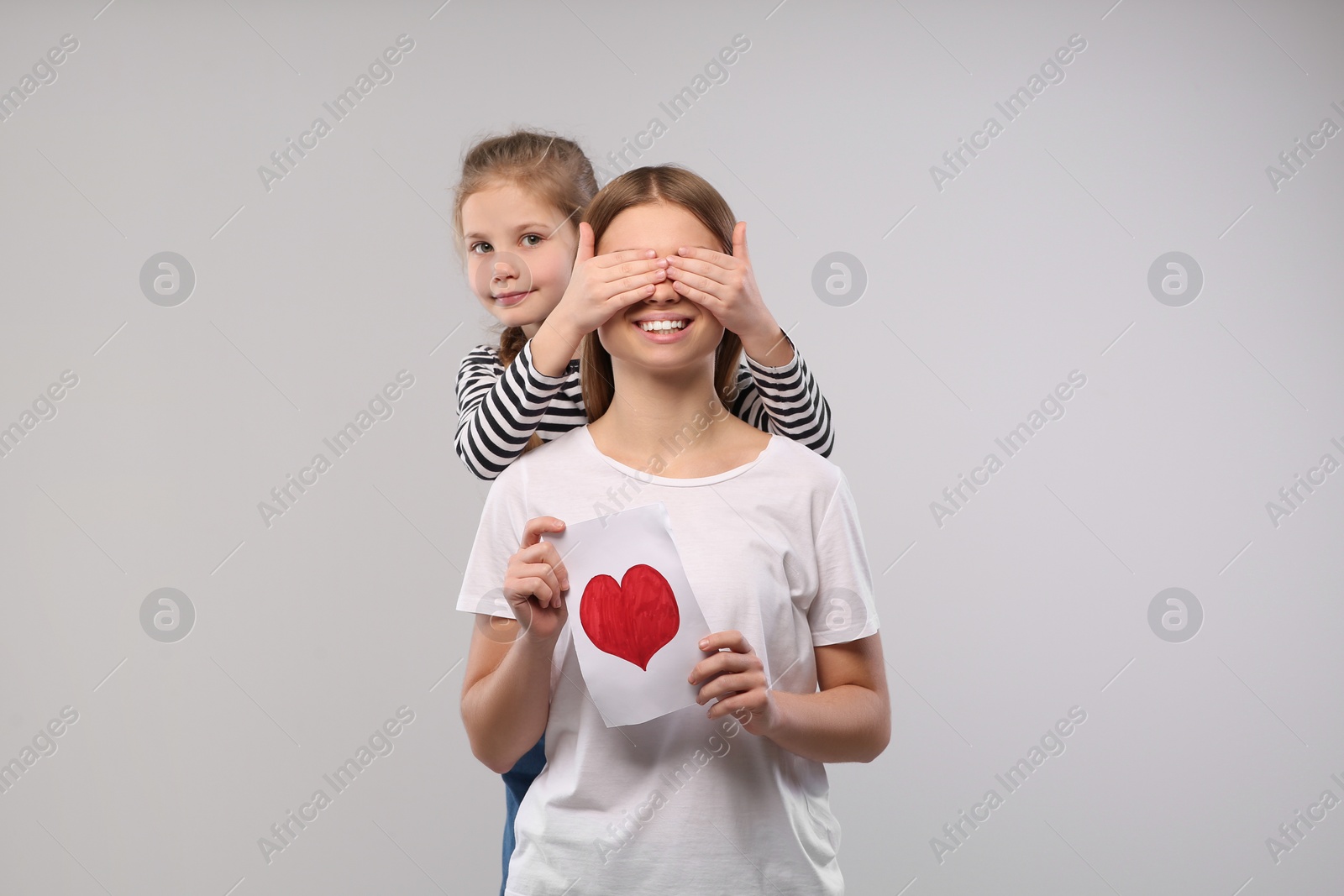 Photo of Little daughter congratulating her mom with postcard on white background, space for text. Happy Mother's Day