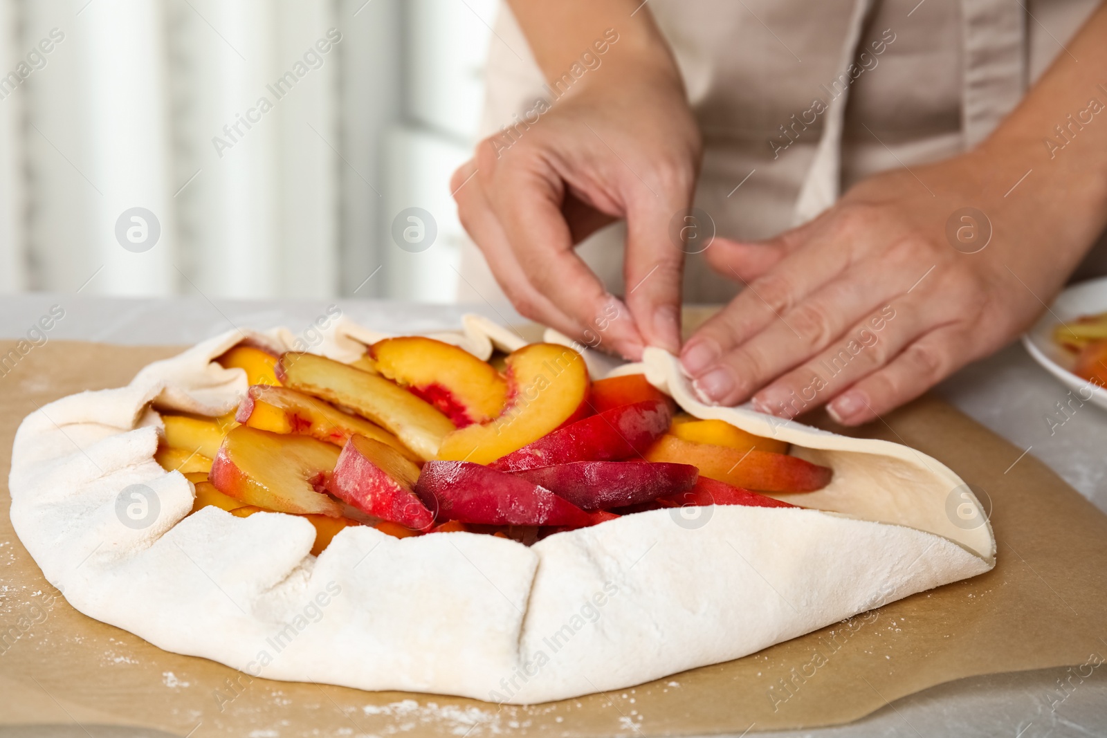 Photo of Woman making peach pie at kitchen table, closeup