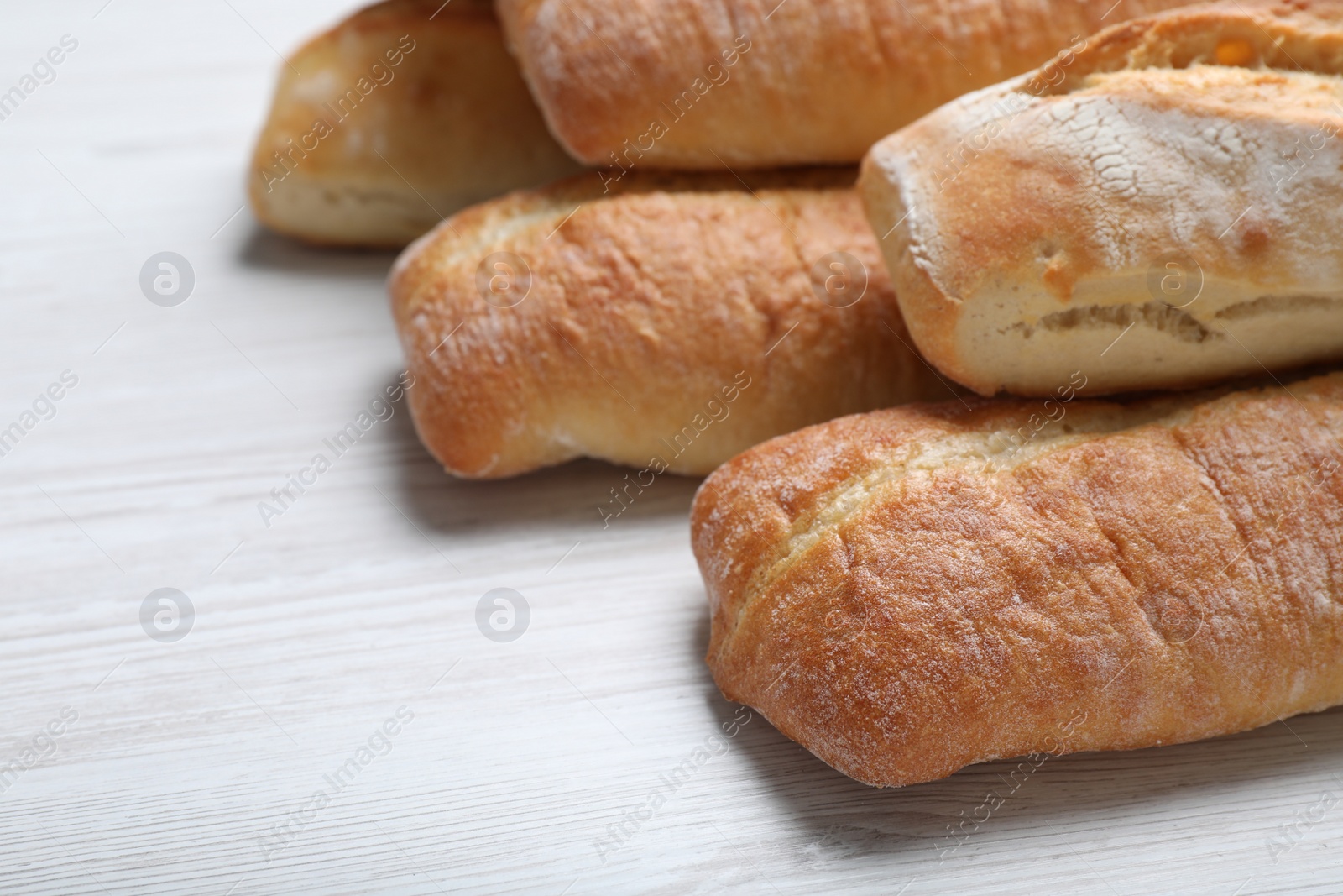 Photo of Tasty baguettes on white wooden table, closeup. Space for text