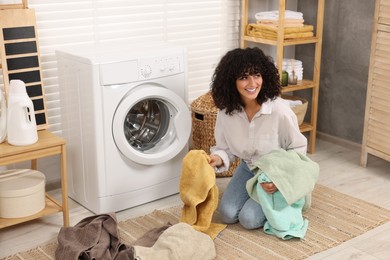 Woman with laundry near washing machine indoors