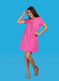 Young woman wearing pink dress on light blue background
