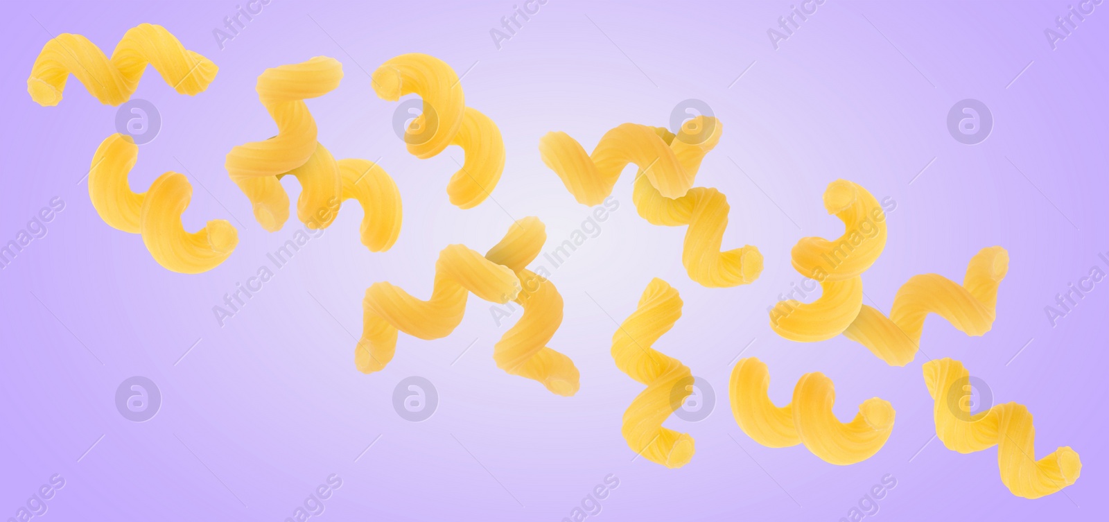 Image of Raw cavatappi pasta falling on violet background