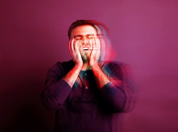 Image of Man suffering from paranoia on magenta background, glitch effect