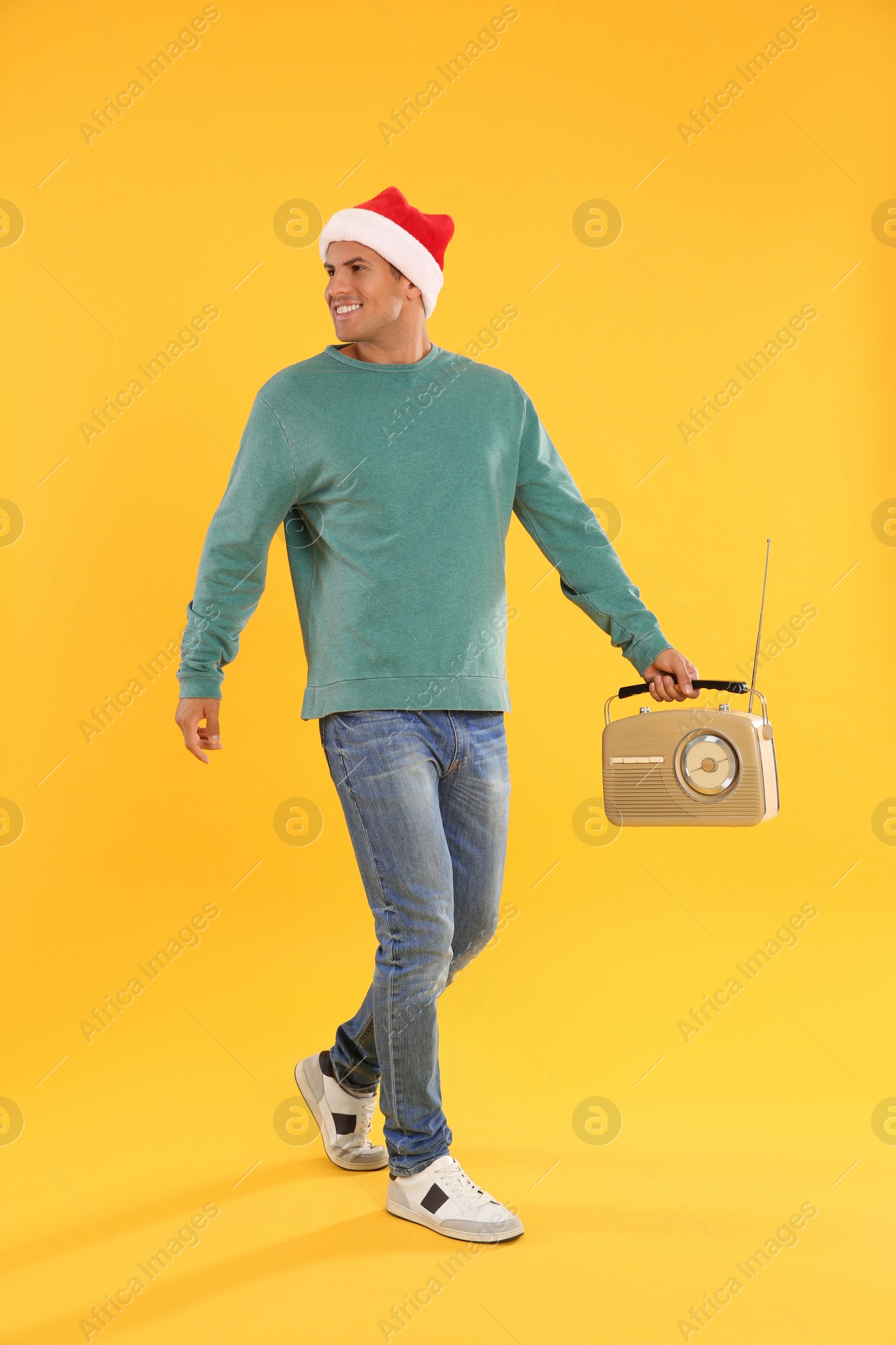 Photo of Happy man with vintage radio on yellow background. Christmas music