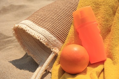 Photo of Beach bag, sunscreen and other accessories on sand, closeup