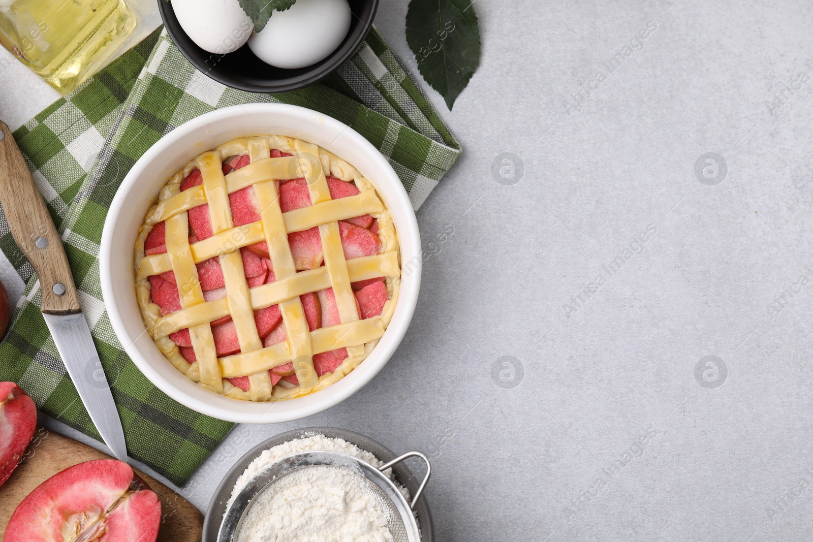 Photo of Flat lay composition with raw apple pie and ingredients on light grey textured table. Space for text