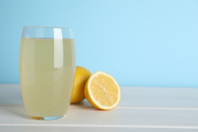 Photo of Glass of lemonade and fresh fruits on white wooden table. Space for text