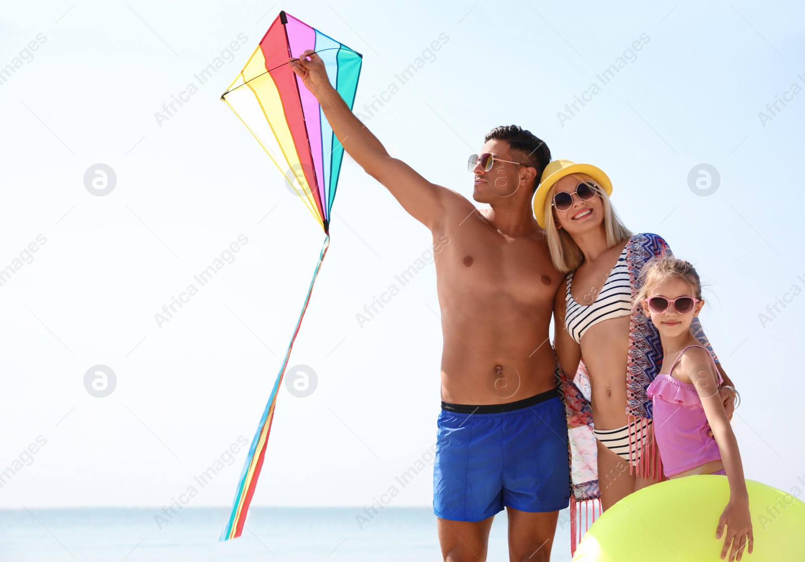 Photo of Happy family with inflatable ring and kite at beach on sunny day